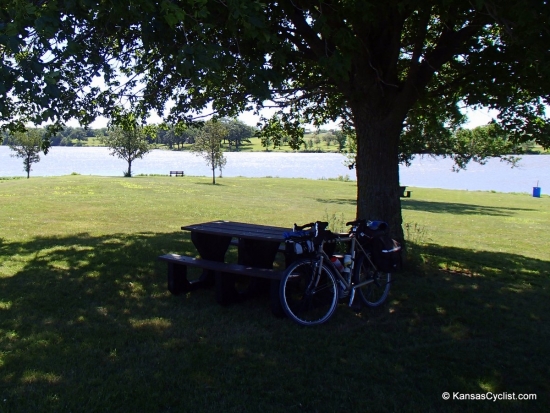 Atchison County Lake - Campsite - This is a typical campsite at Atchison County Lake, with a picnic table, grass, share, easy access to the lake, and nearby trash can.
