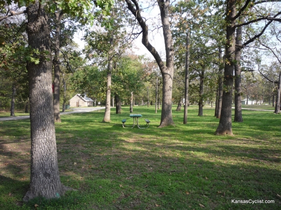 Camp Hunter - Camping Area - This is a view of one of the tent camping areas at Camp Hunter Park in Humboldt, Kansas. There are picnic tables, trash bins, and electricity nearby, with plenty of grass and shade trees.