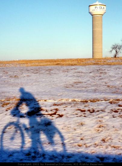 Paola Shadow Rider - A bicyclist rides through a snow-covered landscape in Paola, Kansas.