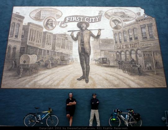 Leavenworth First City Mural - Bicycle tourists pose beneath the 'First City' mural in Leavenworth, Kansas. The mural depicts 'Buffalo Bill', an early lawman in what was the first city incorporated in the state of Kansas.