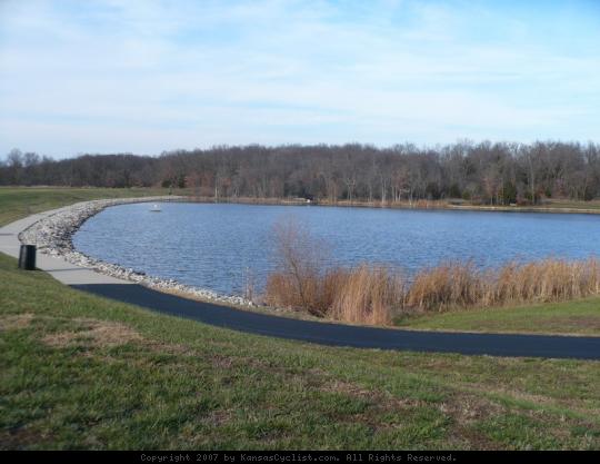 Kill Creek Park 2007 - Kill Creek Lake, a small 28-acre structure with a swimming beach and marina, viewed from the southwest corner of the dam, with paved pathway in the foreground.
