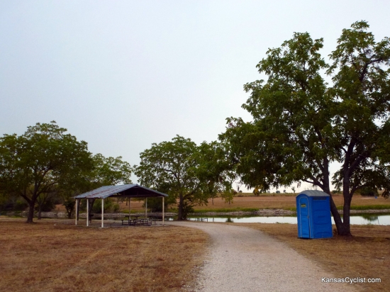Richmond City Lake - Shelter - This photo shows one of the shelters at Richmond City Lake, along with a porta-potty, picnic tables, and grill. There is no drinking water or electricity available.
